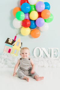 Boy celebrating first birthday with balloon house backdrop in Kingston studio