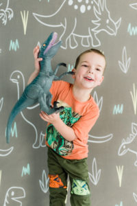 Little boy posing with dinosaur-themed backdrop during Kingston studio session