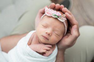 Newborn baby girl's head cradled in father's hands, Knoxville newborn portrait