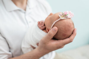 Newborn baby girl's head close up while cradled in father's hands, Knoxville newborn portrait