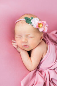 Newborn baby girl lying on her belly wearing a floral tieback, Knoxville newborn photography