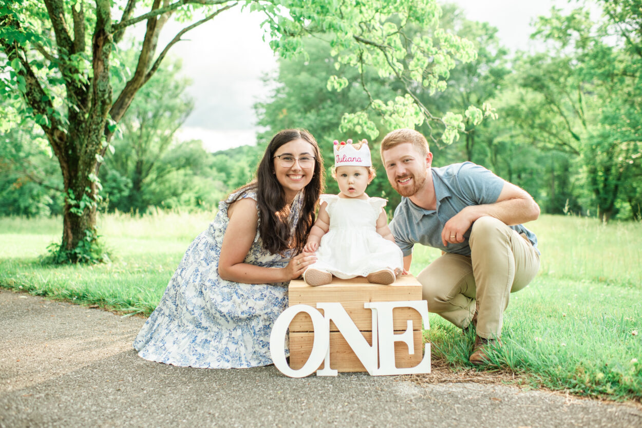 Mom and dad with Juliana sitting on box with ONE letters, Harriman first birthday session