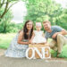 Mom and dad with Juliana sitting on box with ONE letters, Harriman first birthday session
