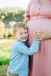 Big brother Henry smiling with hand on mom's baby bump, Knoxville maternity session