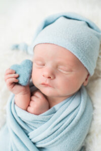 Newborn baby boy holding blue heart prop, Knoxville newborn photography studio