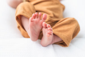 Newborn baby boy's feet in orange overalls, Knoxville newborn photography detail shot