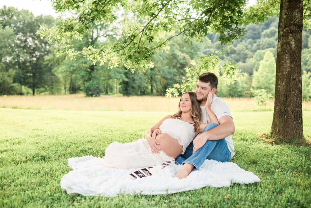 Expecting mom and dad sitting together on a blanket during a maternity session at Lakeshore Park in Harriman, TN