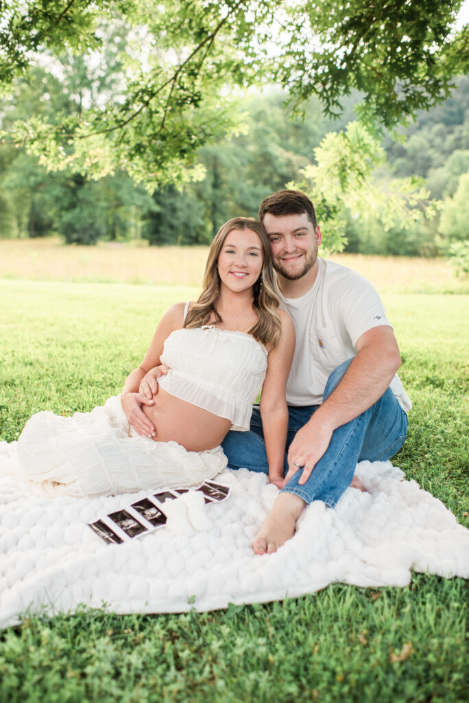 Expecting mom and dad smiling at the camera during a maternity session at Lakeshore Park in Harriman, TN