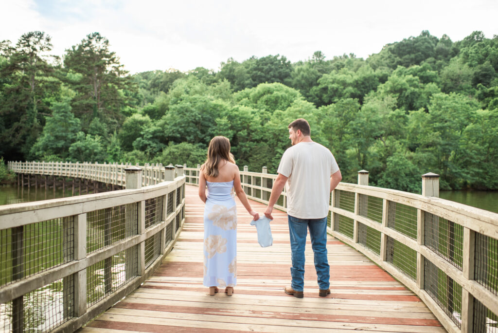 Expecting mom and dad holding a baby onesie during a maternity session in Harriman, TN