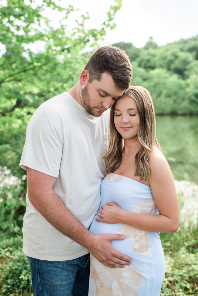 Mom and dad-to-be smiling down at her baby bump during a maternity session in Harriman, TN