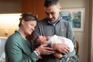 Mom and dad together holding and looking at newborn baby during Fresh 48 session