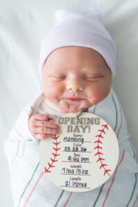 Newborn baby in hospital hat and swaddle with name sign during Fresh 48 session