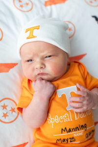 Newborn baby in Tennessee-themed onesie and hat during Fresh 48 photo session