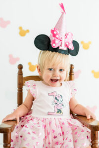 Girl in Minnie Mouse dress and hat celebrating first birthday in Kingston studio