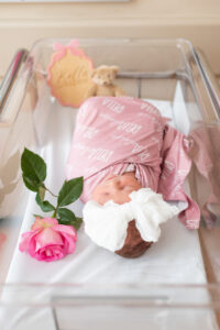 Newborn baby in hospital bassinet with rose and name sign during Fresh 48 session