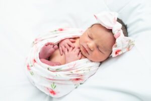 Newborn baby swaddled with hands and feet peeking out during hospital session
