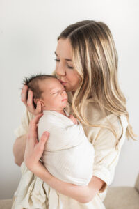Mom kissing her newborn son's head during a studio newborn session with a Knoxville newborn photographer