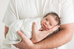 Newborn baby boy wide awake in his father's arms during a Knoxville newborn photography session