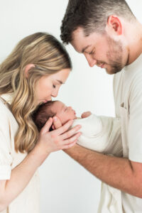 Parents leaning in together over their sleeping newborn son during a studio newborn photography session