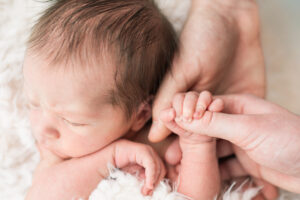 Newborn baby's hand wrapped around parent's finger during a Knoxville newborn photography session