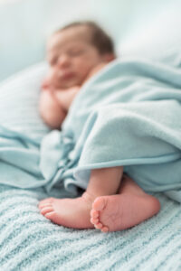 Close-up of newborn baby boy's feet on a light blue blanket during a studio newborn session