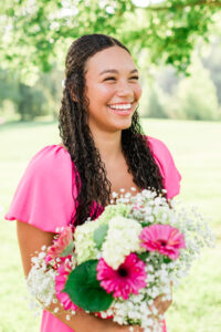 Senior girl laughing while holding a bouquet of pink and white flowers in a sunlit park, Knoxville senior photographer
